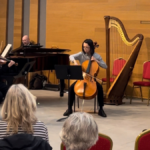 audience in The Stoller Hall atrium watching a cellist and pianist perform