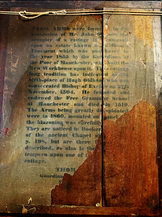 Photo of the damaged printed text on the back of the painting of the Oldham arms.