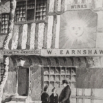 A print depicting the Sun Inn, a leaning timber-framed building. Two stone steps lead up to the door, above which is a sign reading ‘Poets’ Corner’; next to that is another sign depicting a sun with a face.