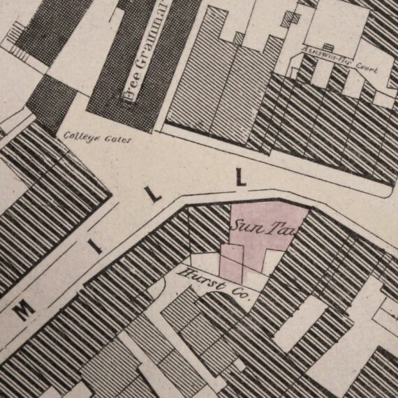 An old map of Manchester that has been coloured in pale pink and blue. It shows the Sun Inn opposite the entrance to Chetham's Library on Long Millgate.