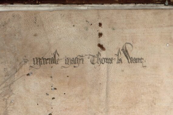 The head of a page from a medieval manuscript. Gothic script in black ink reads ‘Mariale Magistri Thome la Warre’. Just above this are three holes in the parchment, each surrounded by a rust stain, and in perfect alignment. 