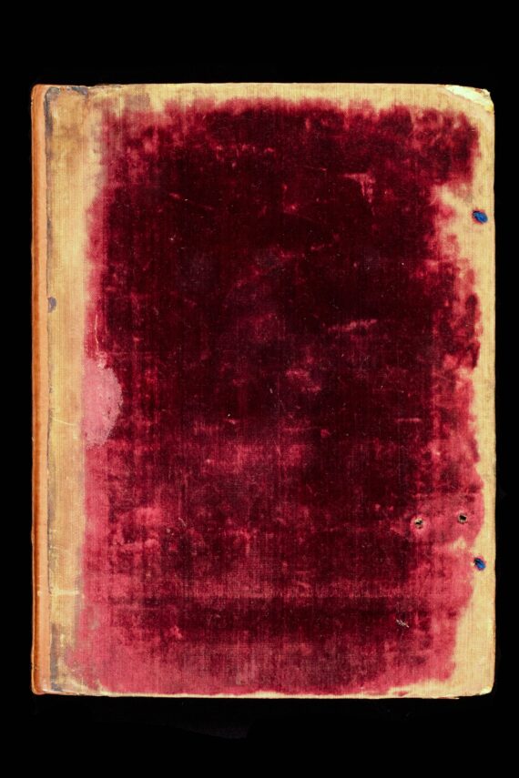 The cover of a book bound in deep red velvet. Towards the edges of the cover, the velvet has been worn away, and towards the right of the cover (the fore-edge side), two holes are visible where ties were once attached.
