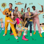 Six musicians against a green and blue backdrop, with cartoon characters