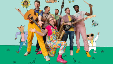 Six musicians against a green and blue backdrop, with cartoon characters