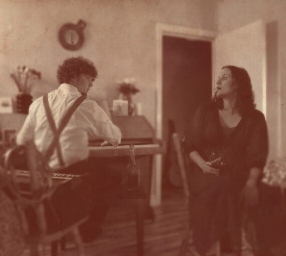 Sepia print photo of musicians Vidar Norheim (seated at piano) and Lizzie Nunnery