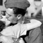 A black and white photo of a man and a woman kissing