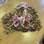 A collection of dried plants and herbs, and small pink cloth bags with pink ribbons