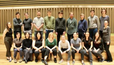 Kantos chamber choir sit on the stage of the Stoller hall