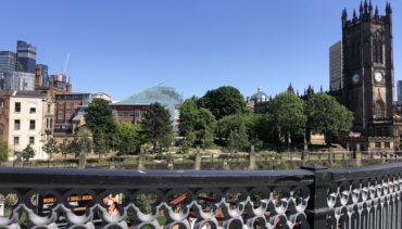 View of Cathedral Gardens and the Cathedral in Manchester against a blue sky