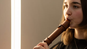 A girl playing a wooden recorder