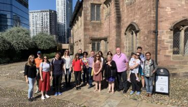 A tour group stands outside Chetham's Medieval buildings in the sunshine