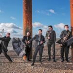 Members of the English Cornett and Sackbut ensemble holding umbrellas and instruments