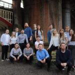 Kantos chamber Choir standing in front a brick backdrop