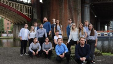Kantos chamber Choir standing in front a brick backdrop