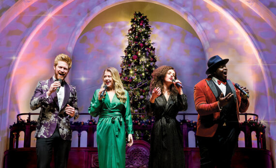 Four singers with a Christmas tree and a pink background