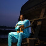 Artist Vieux Farka Toure in a turquoise outfit, with guitar