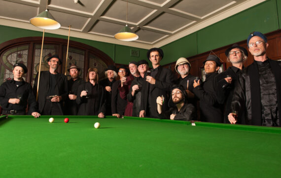 Members of the Spooky Men's chorale around a pool table