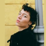 Artist Emily King on a yellow background