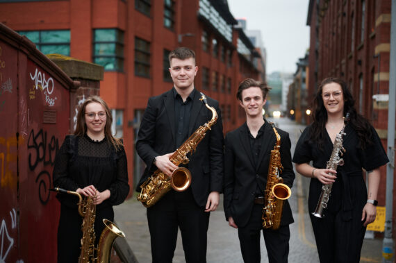 A saxophone quartet, standing outside with instruments