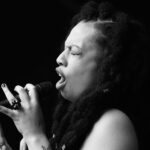 Black and white photo of musician Lady Nade singing into a microphone