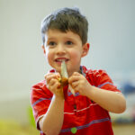 A boy in a red top with a cymbal