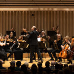 Manchester Camerata performing on a concert hall stage with conductor