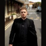 Singer Tom Ball dressed in black suit