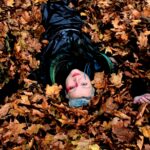 Musician Eliza Carthy lying upside down in orange fallen leaves