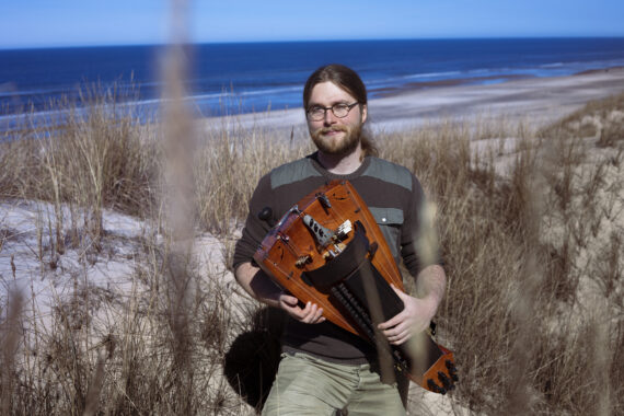 Musician Christian Mohr Levisen on the beach with his hurdy gurdy