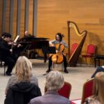 A seated audience watching a pianist and cellist in the Stoller Hall Atrium