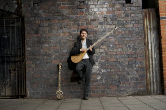 Musician Shohret Nur standing against a brick wall