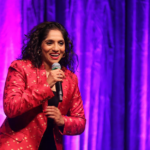 Jamie Lever wearing a red top against a purple backdrop