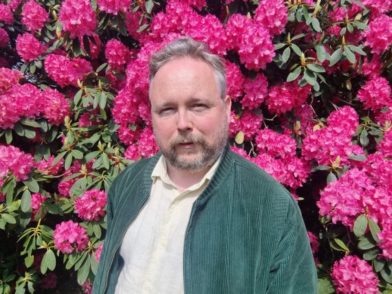 Musician Richard Dawson against a background of pink flowers