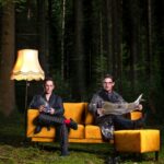 Members of Cafe Del Mundo seated on a sofa against a forest background