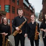 A saxophone quartet, standing outside with instruments