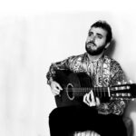 black and white photo of artist Jesús Guerrero playing guitar