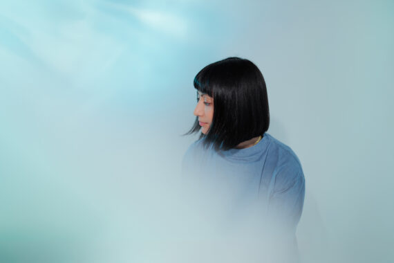 Image of a woman with black hair and a blue top, fading inot a blue background