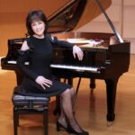 Musician Noriko Ogawa wearing a black dress seated at the piano