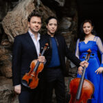 Two men with string instruments and women in a blue dress
