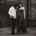 black and white image of a man in a shirt shirt and a woman in a long dress