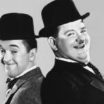 Black and White photo of Laurel and Hardy, two laughing men in suits wearing bowler hats