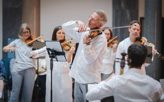 musicians from scottish ensemble dressed in white playing instruments